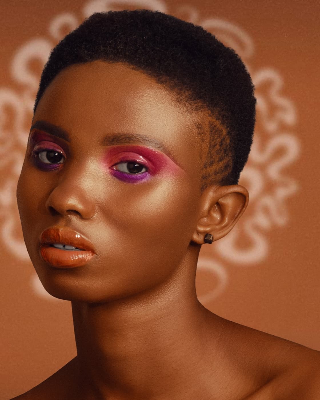 Le même portrait après retouche : fond terracotta travaillé, peau matifiée, maquillage ravivé