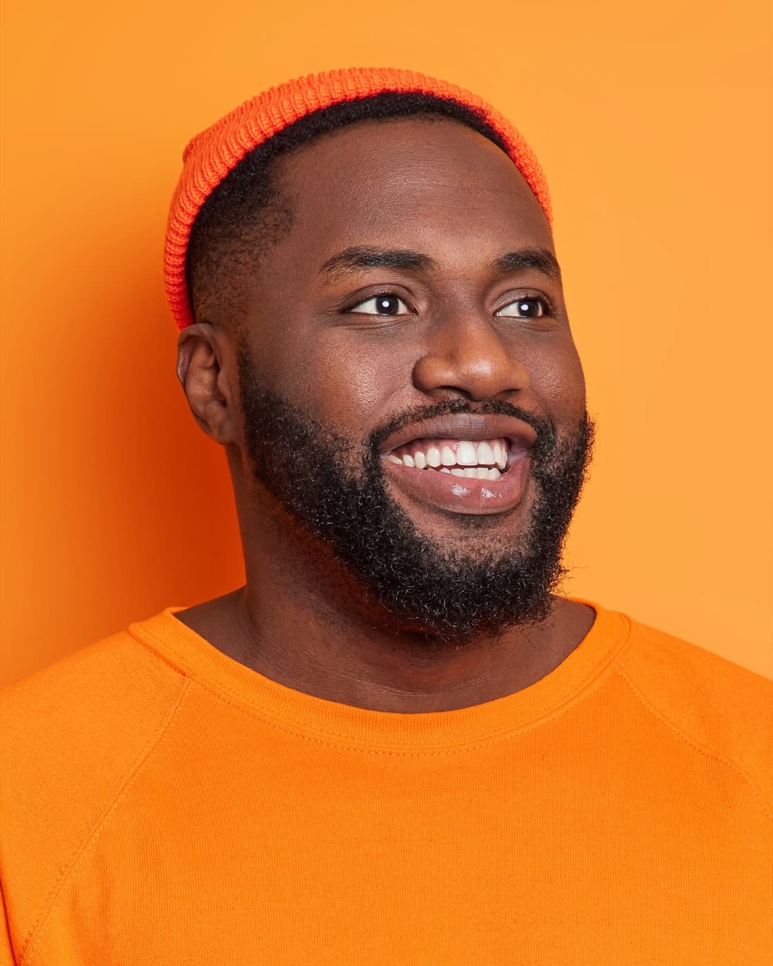 Portrait studio avant retouche : fond orange plat, teint irrégulier